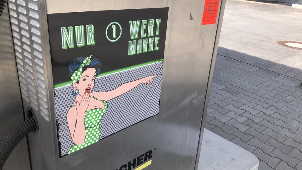 Ein Bildschirm mit der Aufschrift "NUR WERT MARKE" zeigt eine animierte Figur in einem grünen Polka-Dot-Kleid, die mit erhobener Hand auf etwas zeigt.